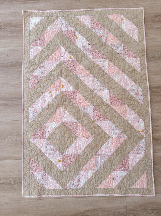 A modern half-square triangle baby quilt in pinks